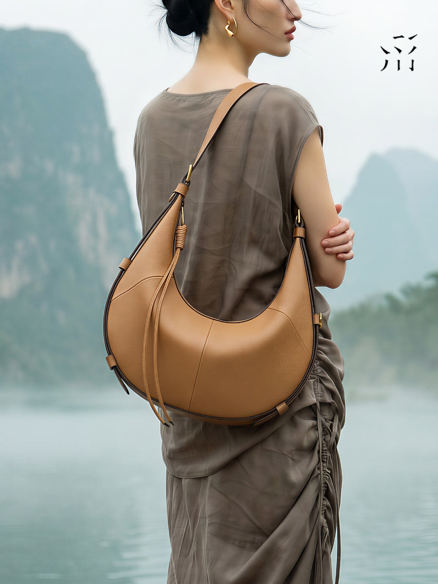 A Small, Sleek Hobo Bag In Vegetable-tanned Top-grain Cowhide, Perfect For Crossbody Or Commuting, Featuring A Summery Crescent Shape, Suitable For Women's Shoulder Or Underarm Wear.