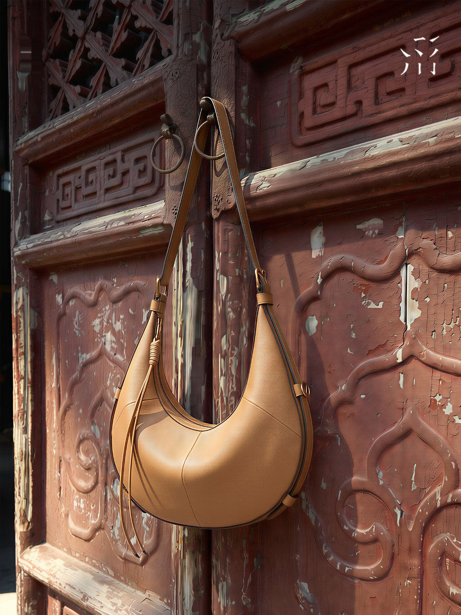 A Small, Sleek Hobo Bag In Vegetable-tanned Top-grain Cowhide, Perfect For Crossbody Or Commuting, Featuring A Summery Crescent Shape, Suitable For Women's Shoulder Or Underarm Wear.