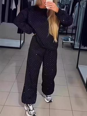 Zweiteiliges Set bestehend aus einem langärmeligen Top mit Rundhalsausschnitt, Strasssteinen und Kordelzug sowie einer Jogginghose.