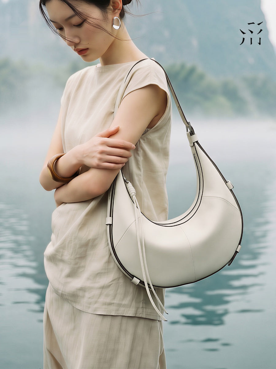 A Small, Sleek Hobo Bag In Vegetable-tanned Top-grain Cowhide, Perfect For Crossbody Or Commuting, Featuring A Summery Crescent Shape, Suitable For Women's Shoulder Or Underarm Wear.