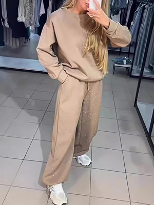 Zweiteiliges Set bestehend aus einem langärmeligen Top mit Rundhalsausschnitt, Strasssteinen und Kordelzug sowie einer Jogginghose.